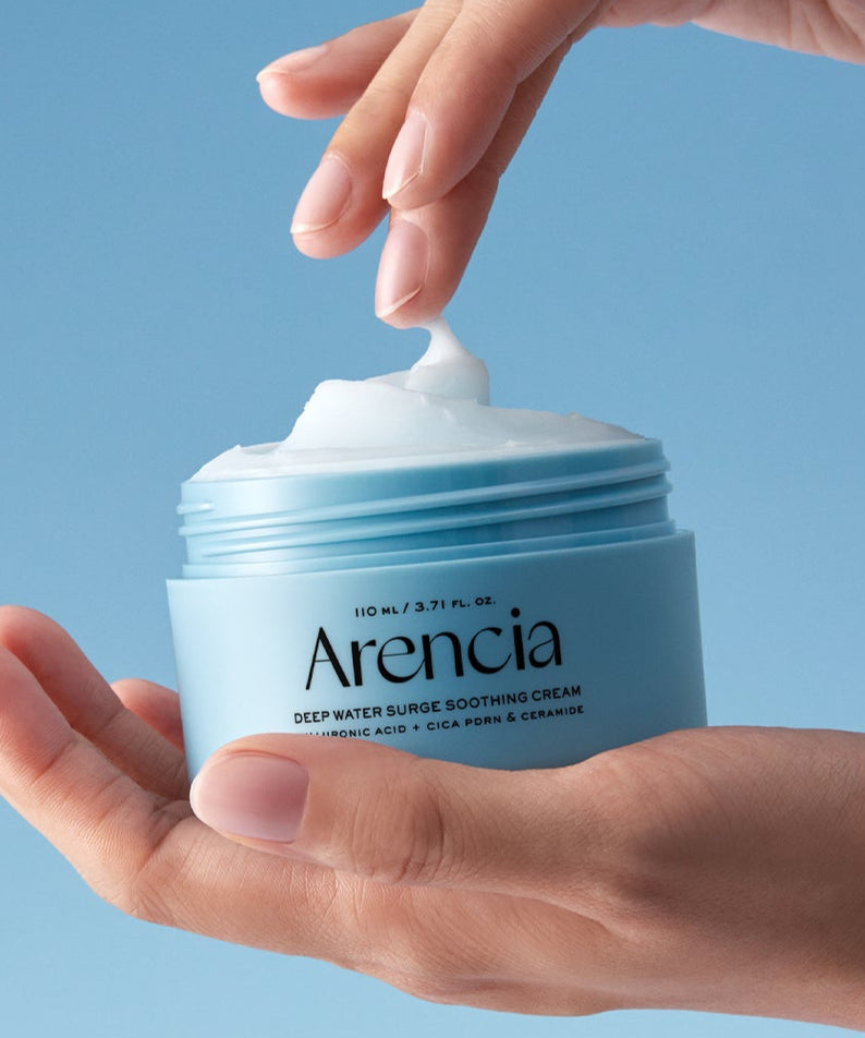 ARENCIA Deep Water Surge Soothing Cream 80ml, pot de crème apaisante, mains appliquant la texture sur fond bleu.
