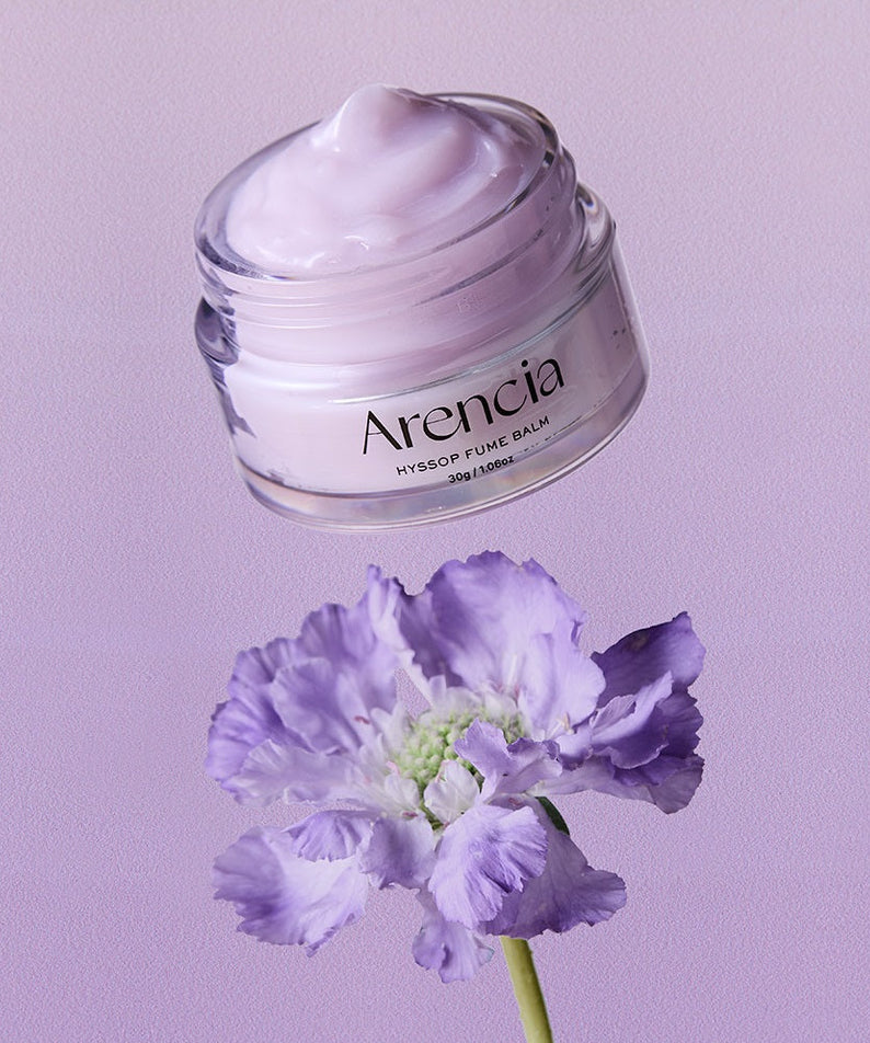Pot de ARENCIA Hyssop Fume Balm 30g sur fond violet avec fleur en avant-plan.