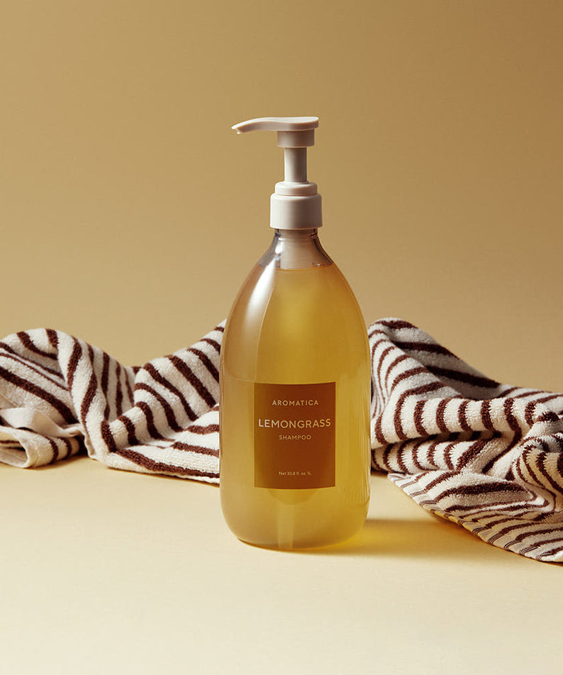AROMATICA Life Lemongrass Shampoo 1000ml de la marque AROMATICA, posé sur serviettes rayées, fond beige clair.
