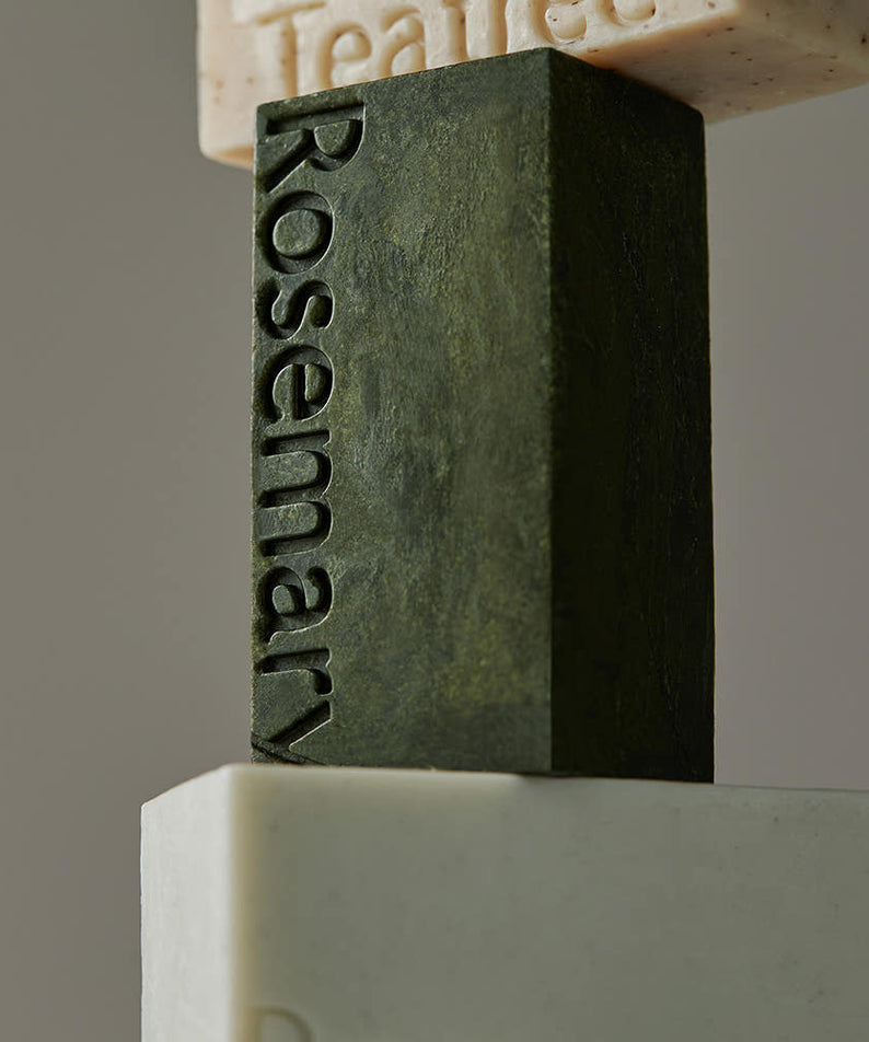 AROMATICA Rosemary Scalp Scaling Shampoo Bar 135g, savon shampooing à la romarin, marque Roti sur bloc vert en studio.