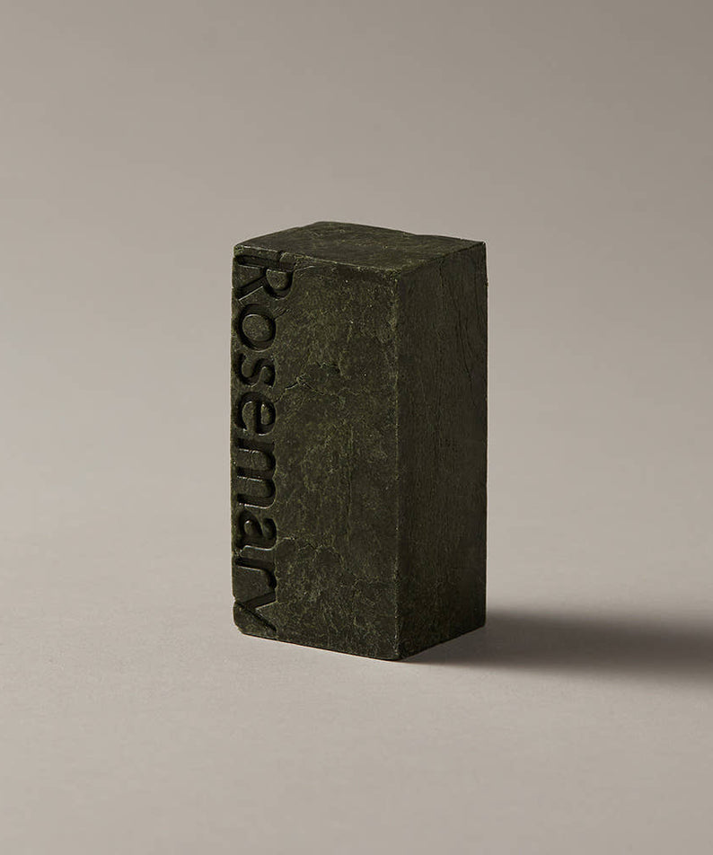 AROMATICA Rosemary Scalp Scaling Shampoo Bar 135g, savon à la romarin vert foncé sur fond clair, marque en relief.