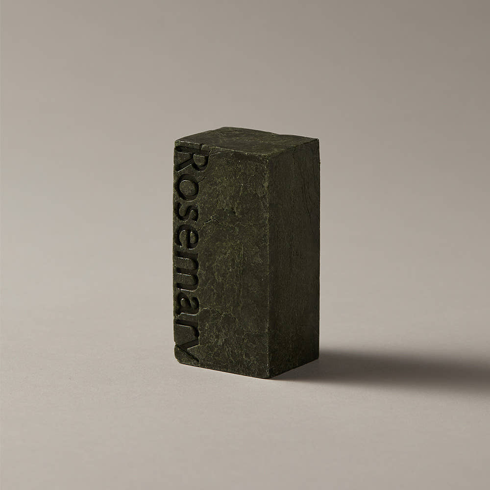 AROMATICA Rosemary Scalp Scaling Shampoo Bar 135g, savon à la romarin vert foncé sur fond clair, marque en relief.