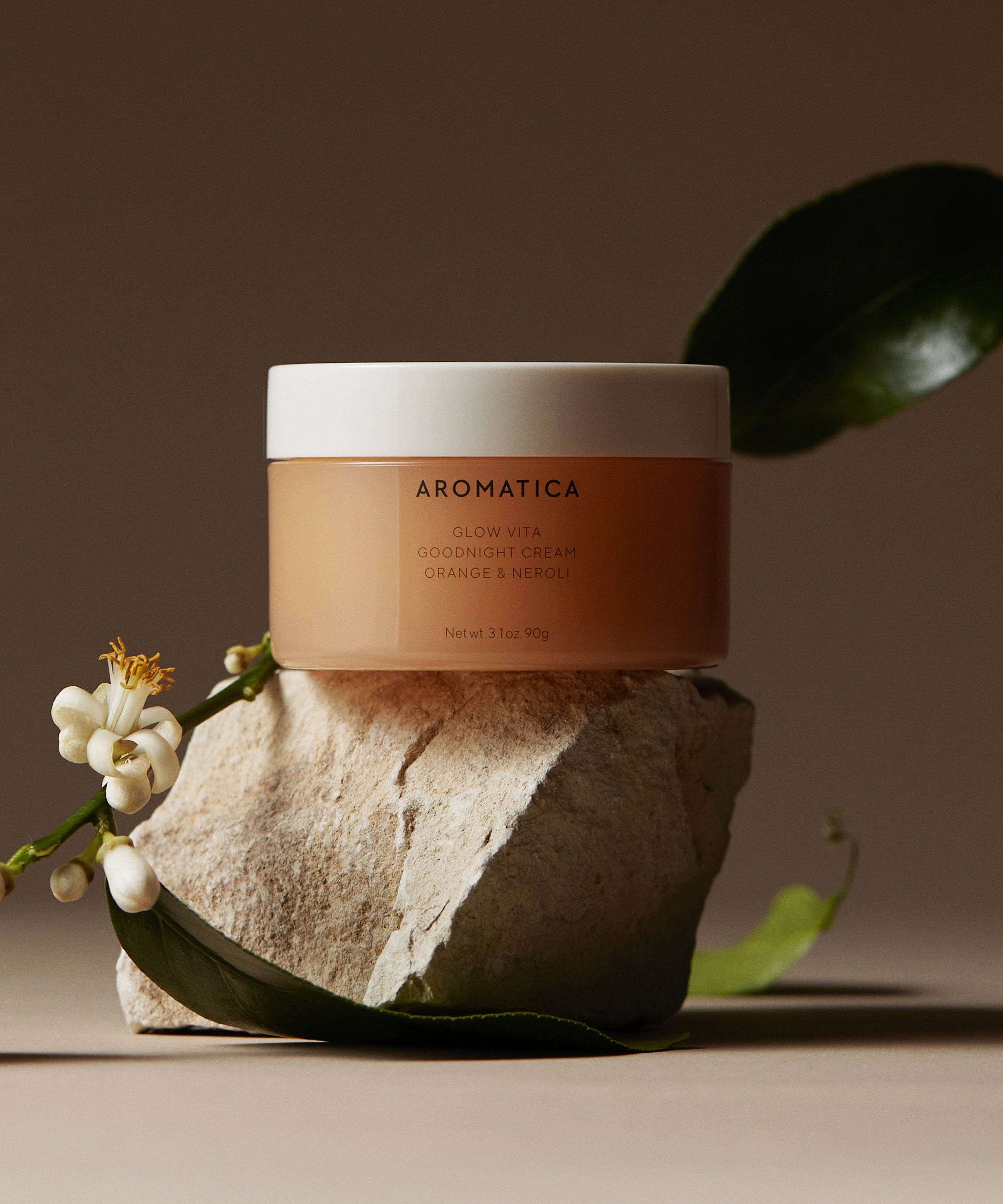 AROMATICA Glow Vita Good Night Cream Orange & Neroli 90G, crème de nuit sur fond beige avec feuille et fleur, marque AROMATICA.