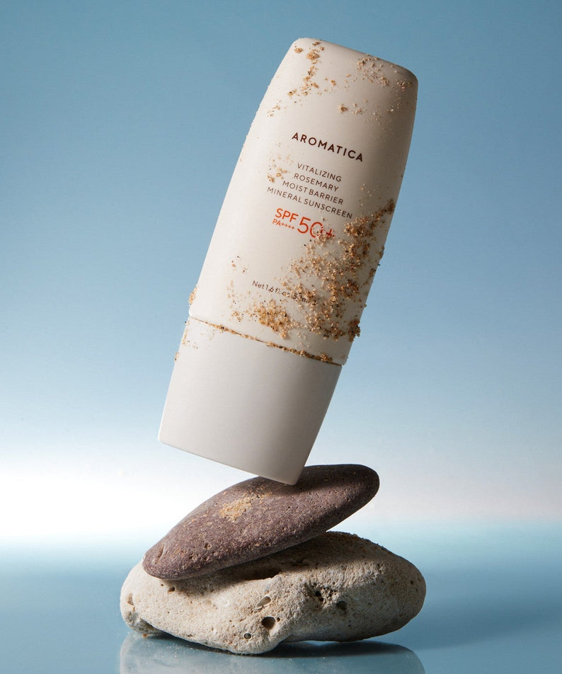 AROMATICA Vitalizing Rosemary Moisture Barrier Sunscreen 50ML : tube crème solaire avec rochers, ciel bleu, marque AROMATICA.