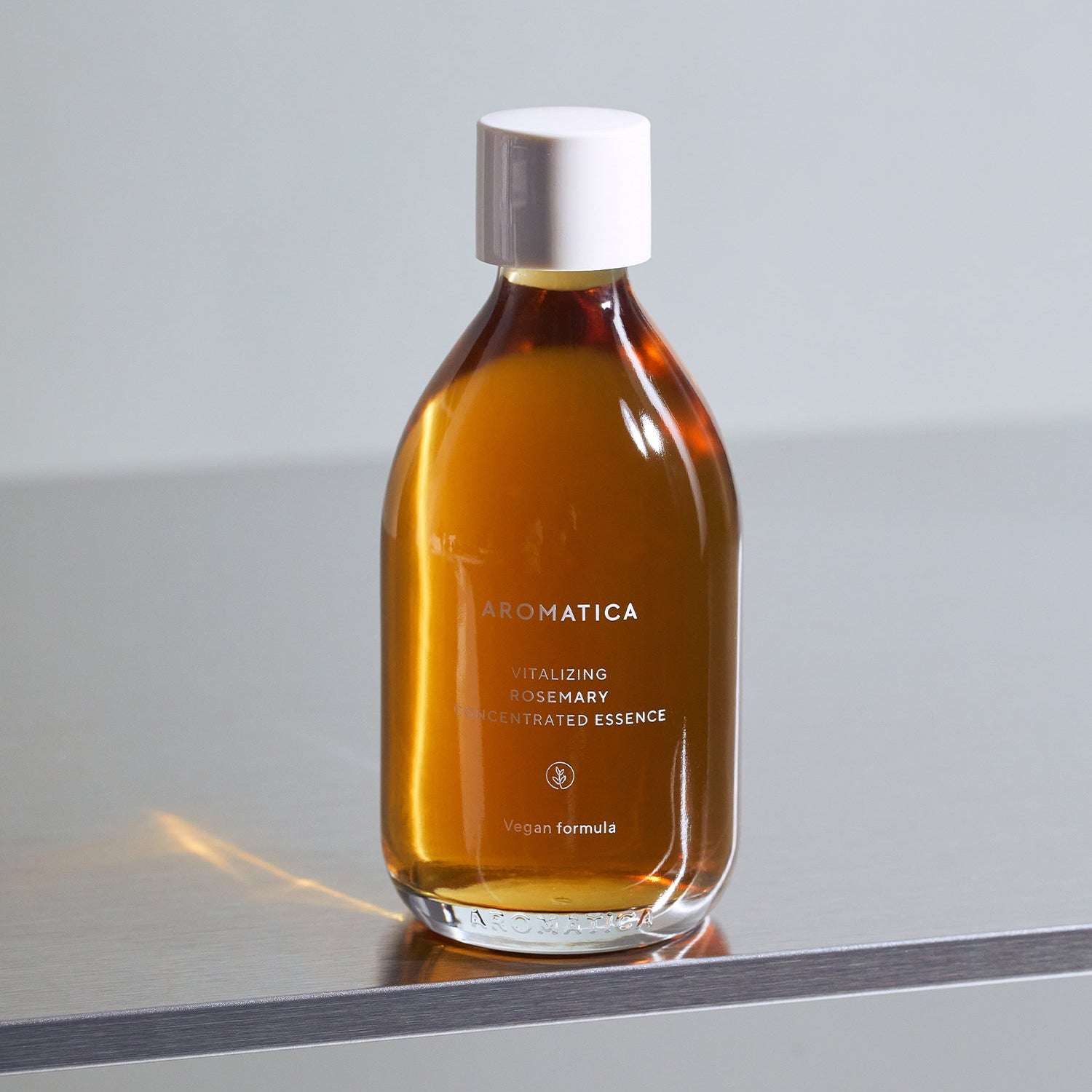 AROMATICA Vitalizing Rosemary Concentrated Essence 200ml, flacon ambré sur table grise, fond clair minimaliste, marque AROMATICA