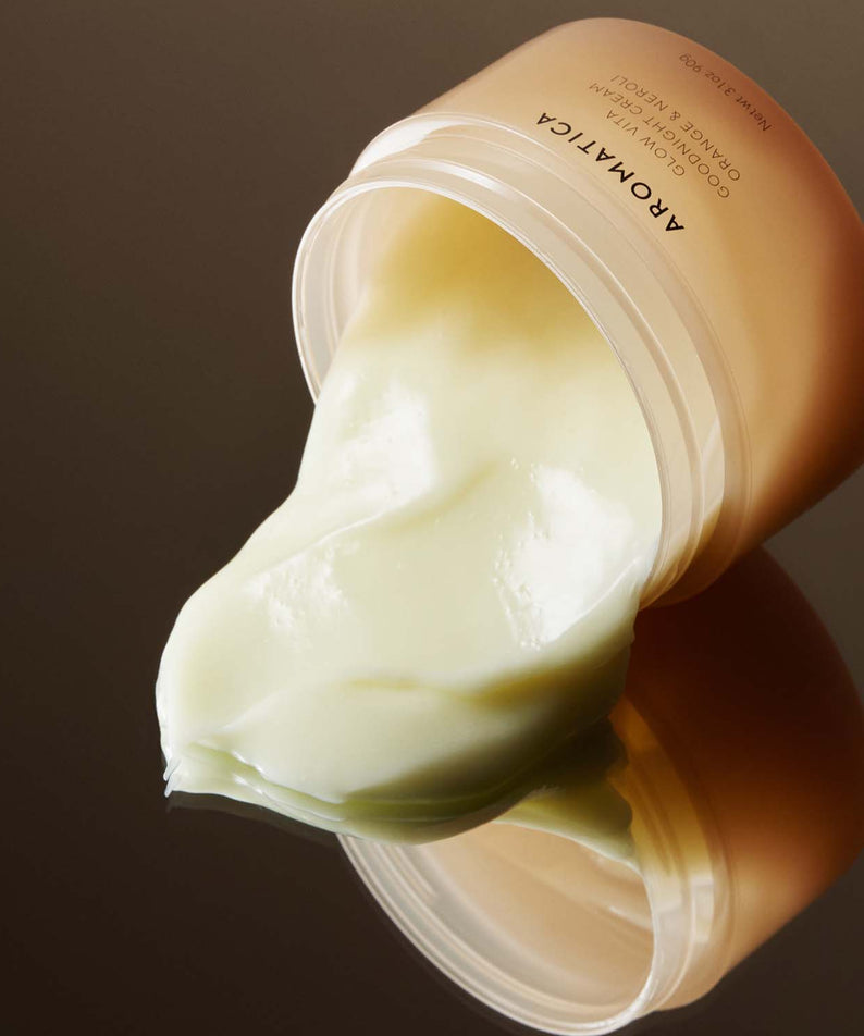 AROMATICA Glow Vita Good Night Cream Orange & Neroli 90G, pot de crème nuit sur fond brun, texture crème blanche.