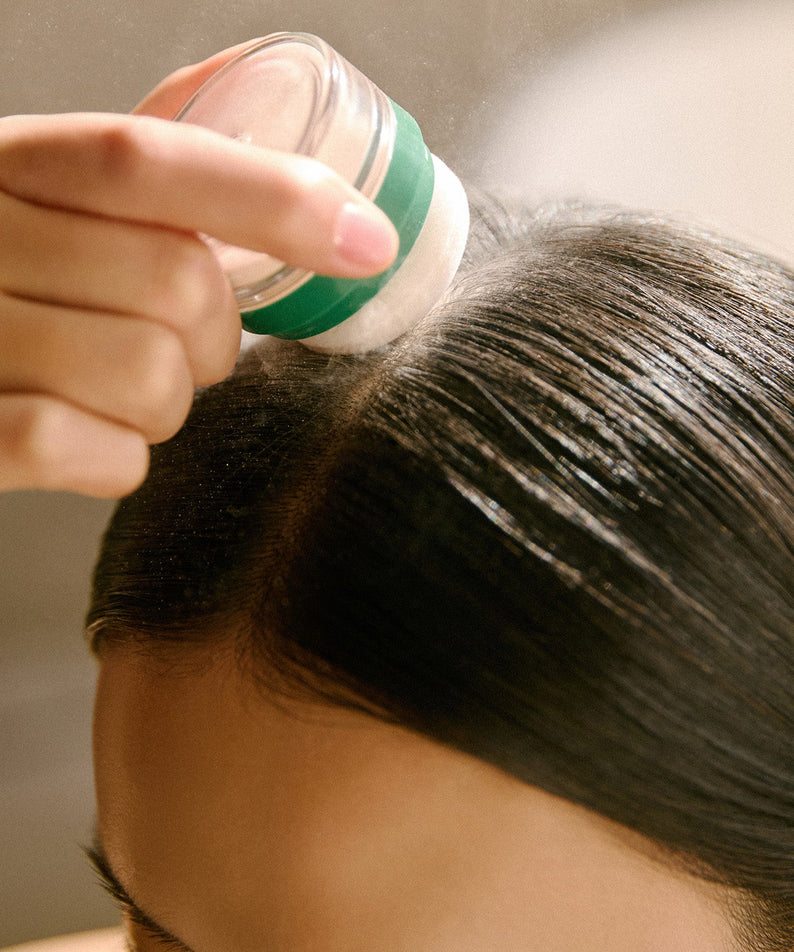 AROMATICA Rosemary Dry Shampoo Powder 10g, main qui applique la poudre sur cheveux, flacon vert, salle de bain
