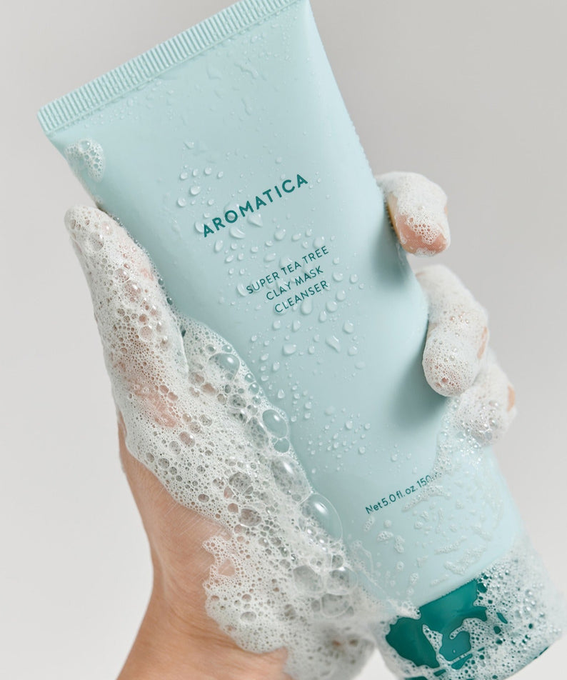 AROMATICA Super Tea Tree Clay Mask Cleanser 150ML de la marque, tube bleu, mains sous mousse sur fond blanc