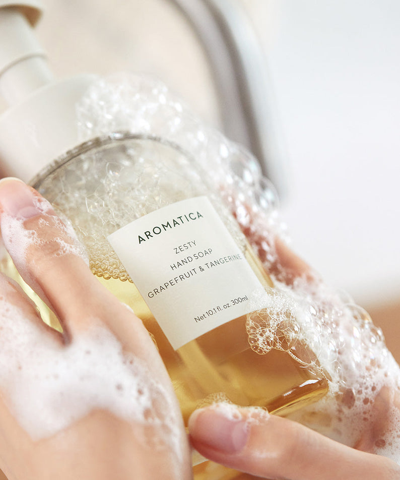 AROMATICA Zesty Hand Soap Grapefruit & Tangerine 300ML, marque sur flacon en mains sous mousse, salle de bain