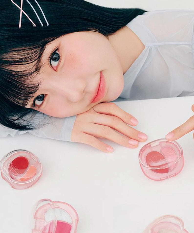 Femme appréciant le A'PIEU Juicy Pang Mood Blending Lip & Cheek Balm, coffret en gros plan.