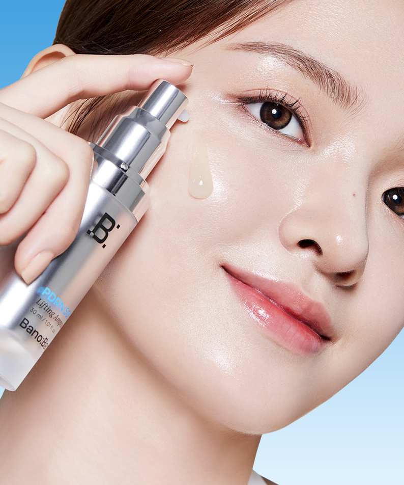 BANOBAGI PDRN 500 Lifting Ampoule 30ml, main applique sur le visage d’une femme, sérum sur peau lumineuse, fond bleu