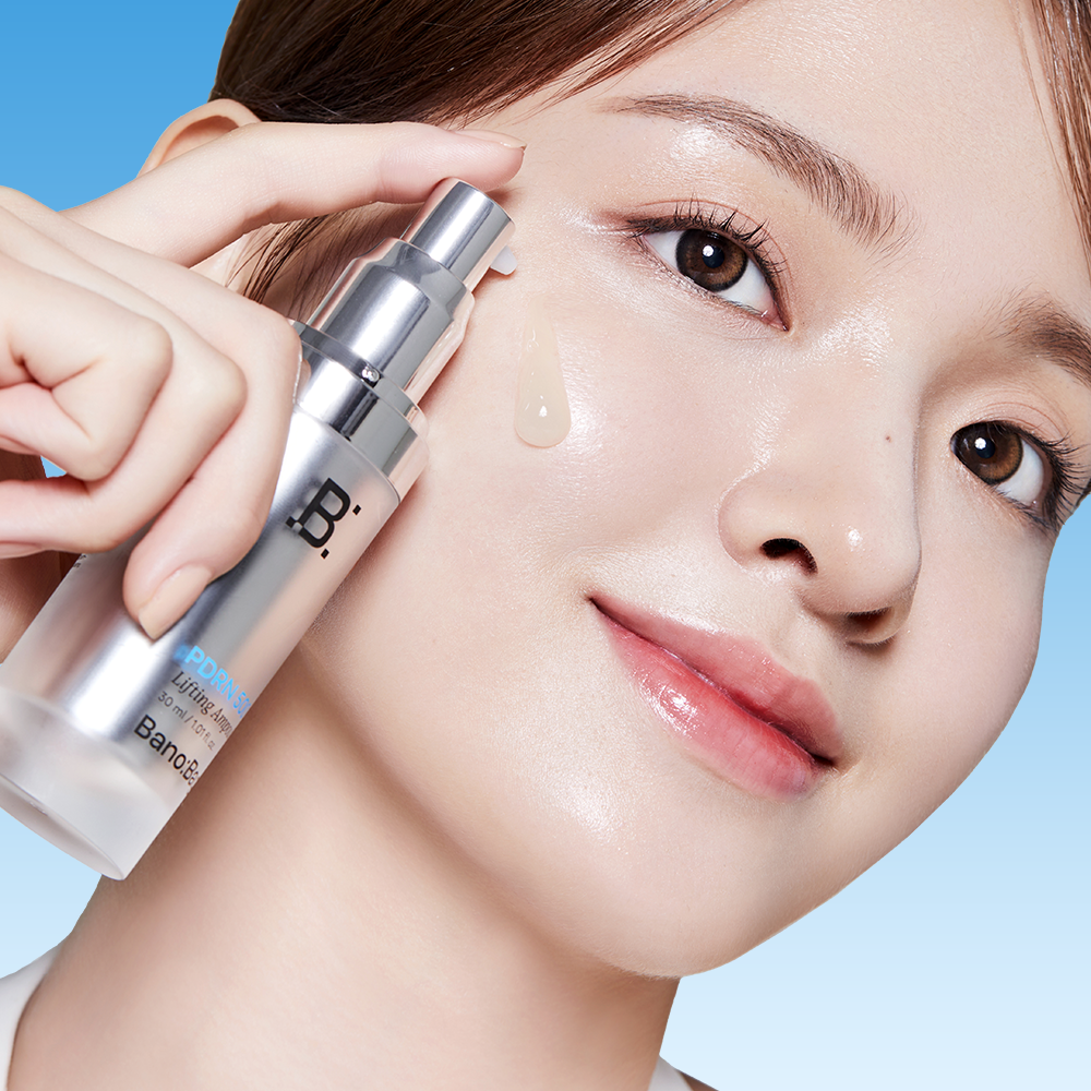 BANOBAGI PDRN 500 Lifting Ampoule 30ml, main applique sur le visage d’une femme, sérum sur peau lumineuse, fond bleu