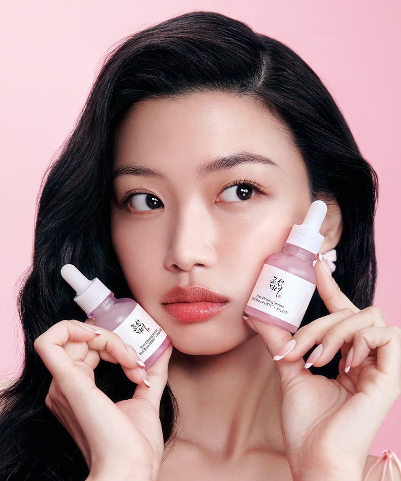 Décris l'image en français en mentionnant le produit, la marque et le contexte visuel : BEAUTY O JOSEON Red Bean PDRN Pore Firming Serum 30mL, flacons tenus par une femme sur fond rose.