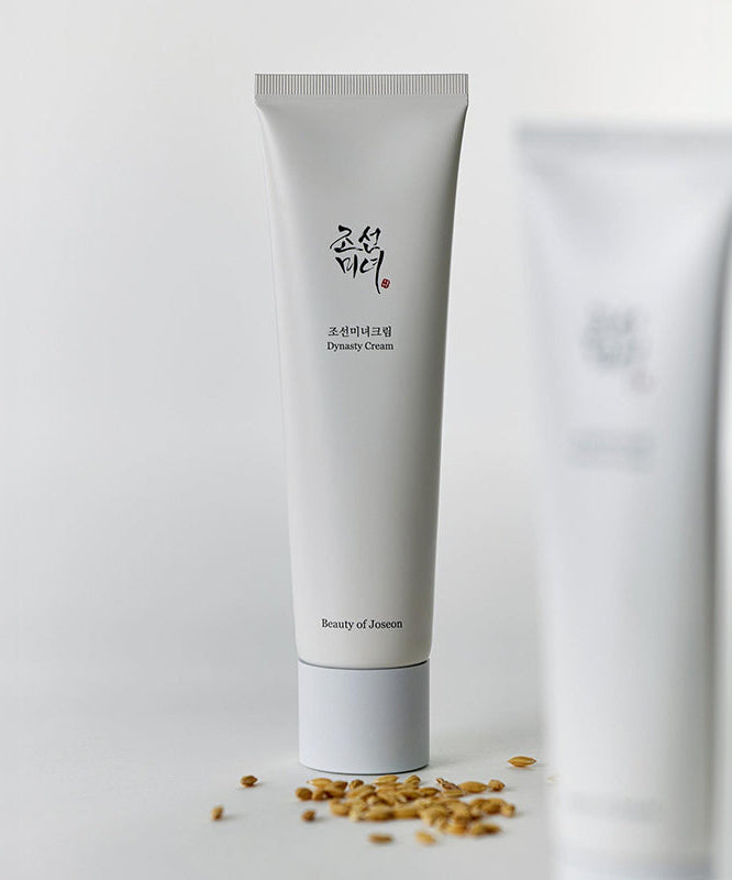 BEAUTY OF JOSEON Dynasty Cream 100ml, tube crème de la marque, posée sur fond blanc avec flocons de céréales.