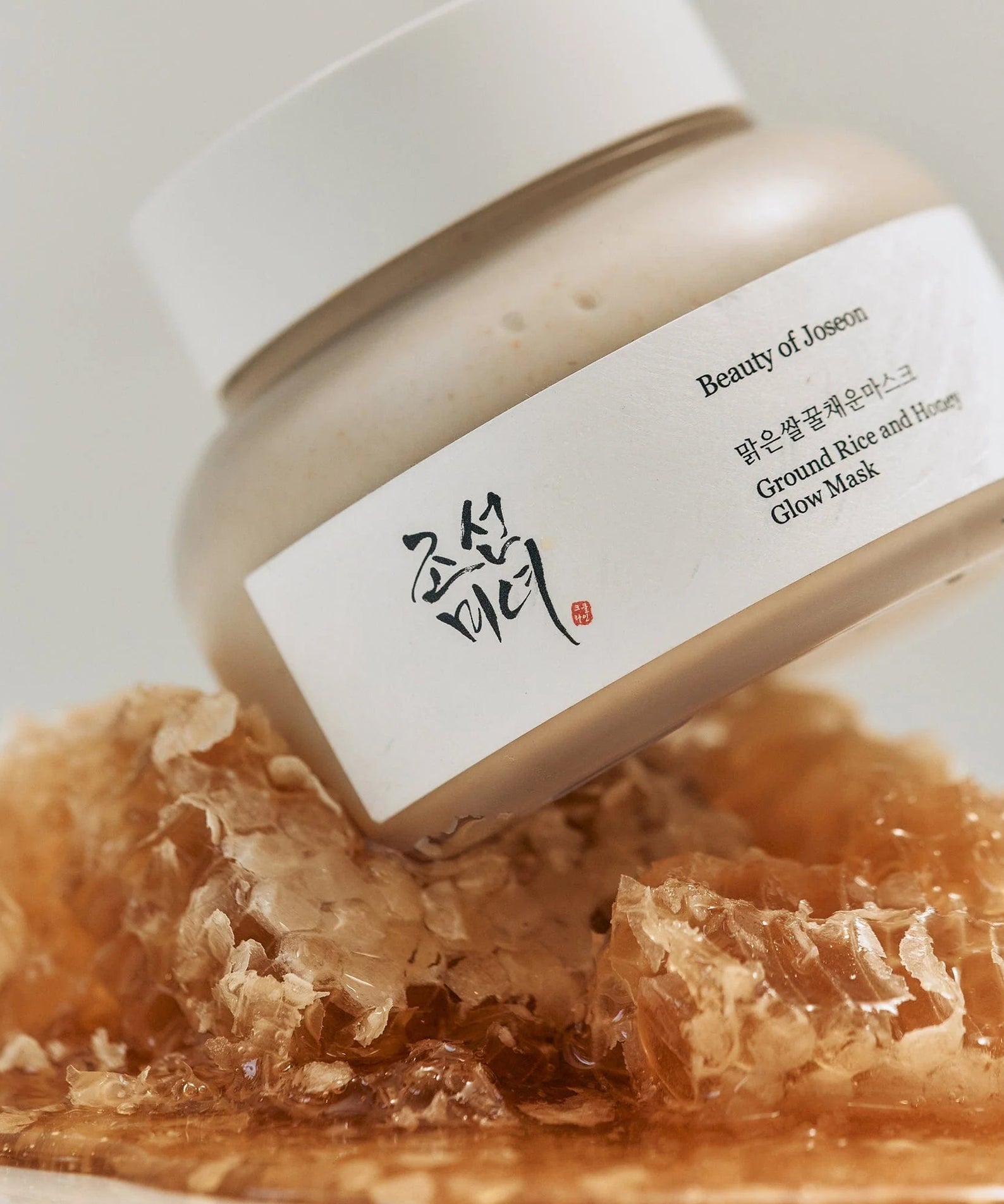 Décris l'image en français : BEAUTY OF JOSEON Ground Rice and Honey Glow Mask 150ml, pot et texture au miel.