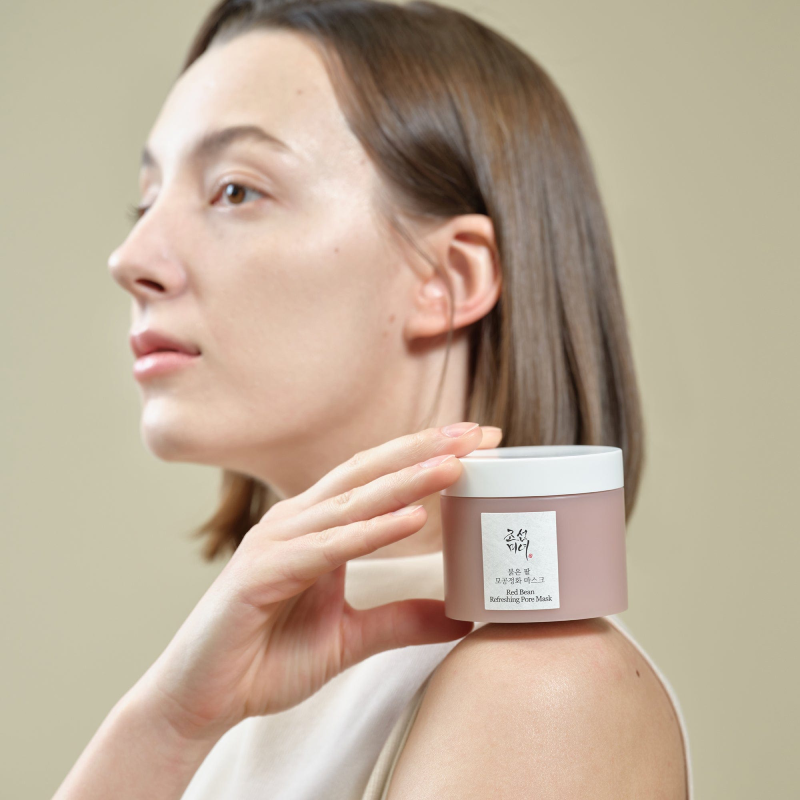 BEAUTY OF JOSEON Red Bean Refreshing Pore Mask 140ml : femme applique le masque sur le visage, pot blanc sur fond clair