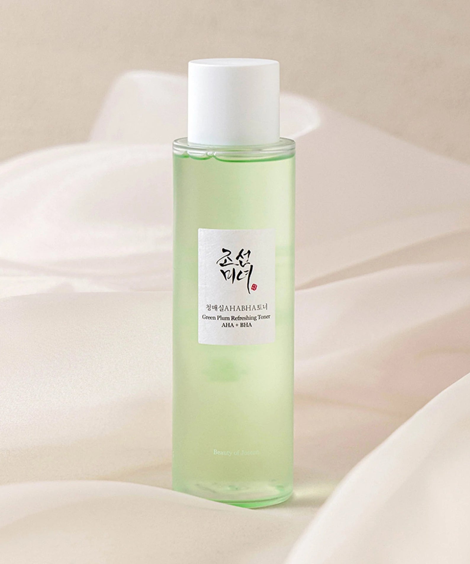 Flacon de BEAUTY OF JOSEON Green Plum Refreshing Toner AHA + BHA 150ml sur tissu en arrière-plan