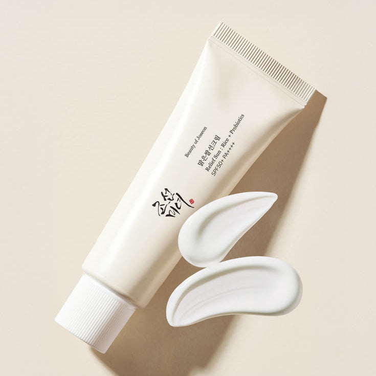 Décrivez l'image en français: BEAUTY OF JOSEON Relief Sun Rice Sun Cream 50ml, tube crème et texture blanche sur fond clair.