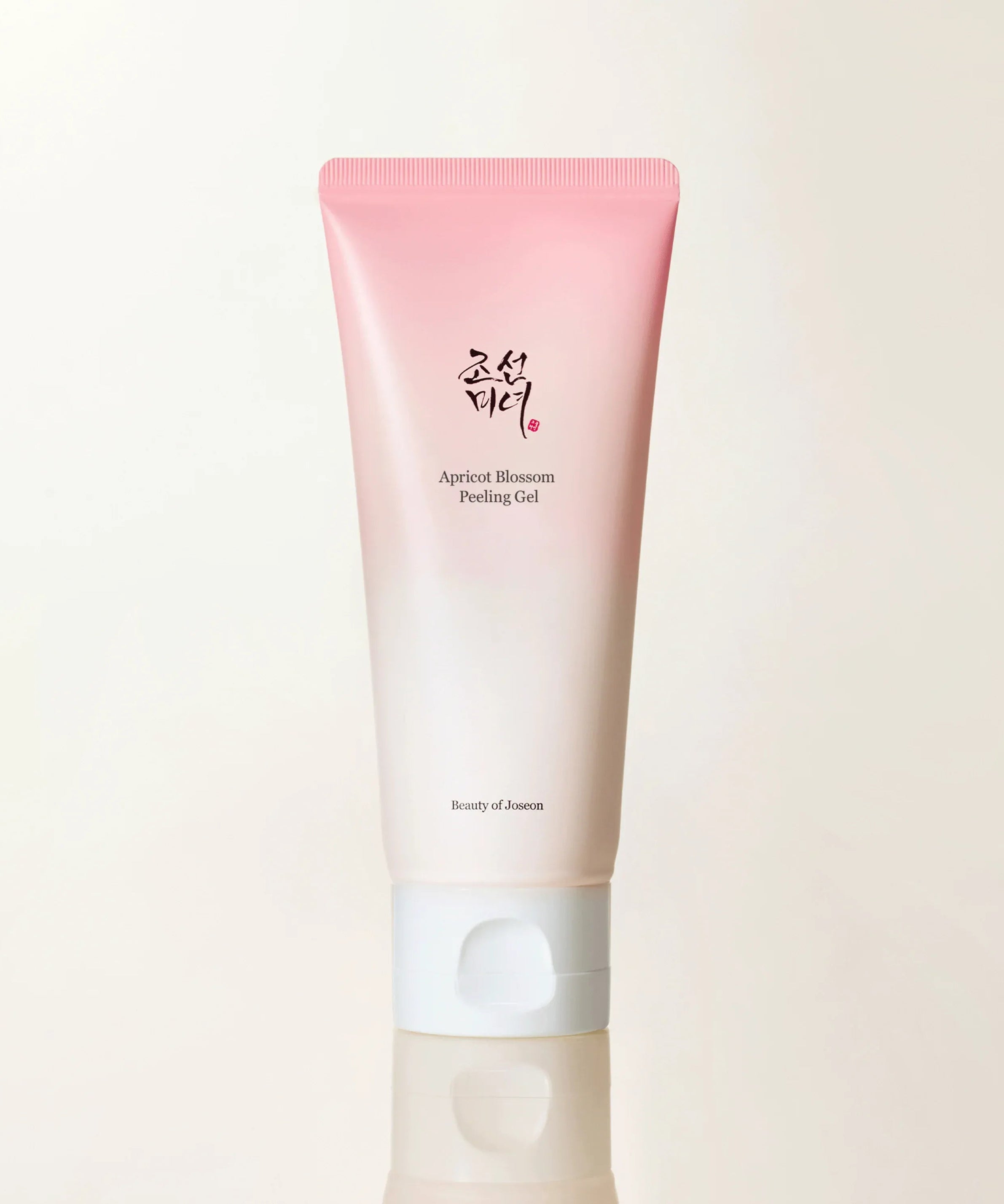 Décris l'image en français: BEAUTY OF JOSEON Apricot Blossom Peeling Gel 100ml, tube rose sur fond blanc, marque Beauty of Joseon.