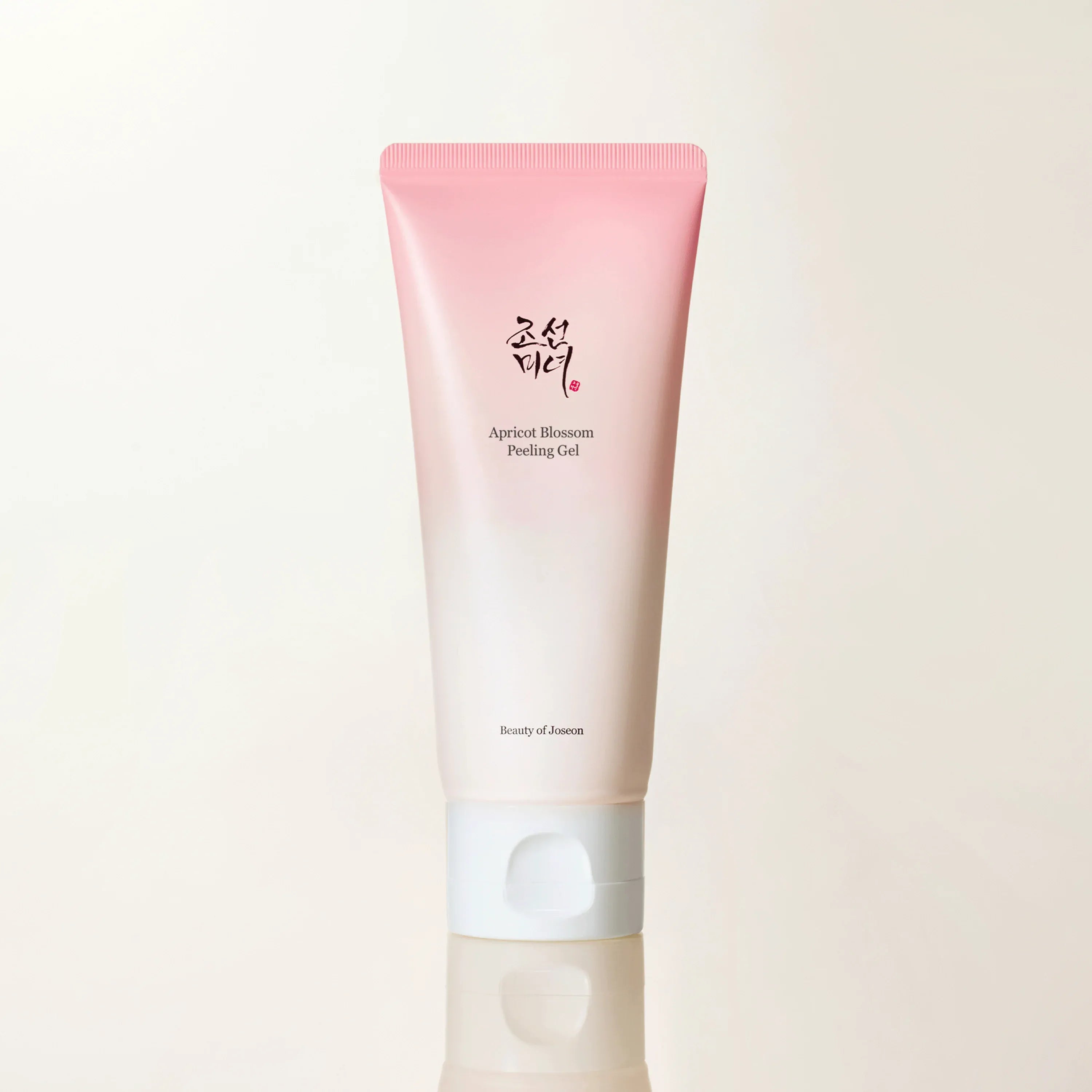 Décris l'image en français: BEAUTY OF JOSEON Apricot Blossom Peeling Gel 100ml, tube rose sur fond blanc, marque Beauty of Joseon.