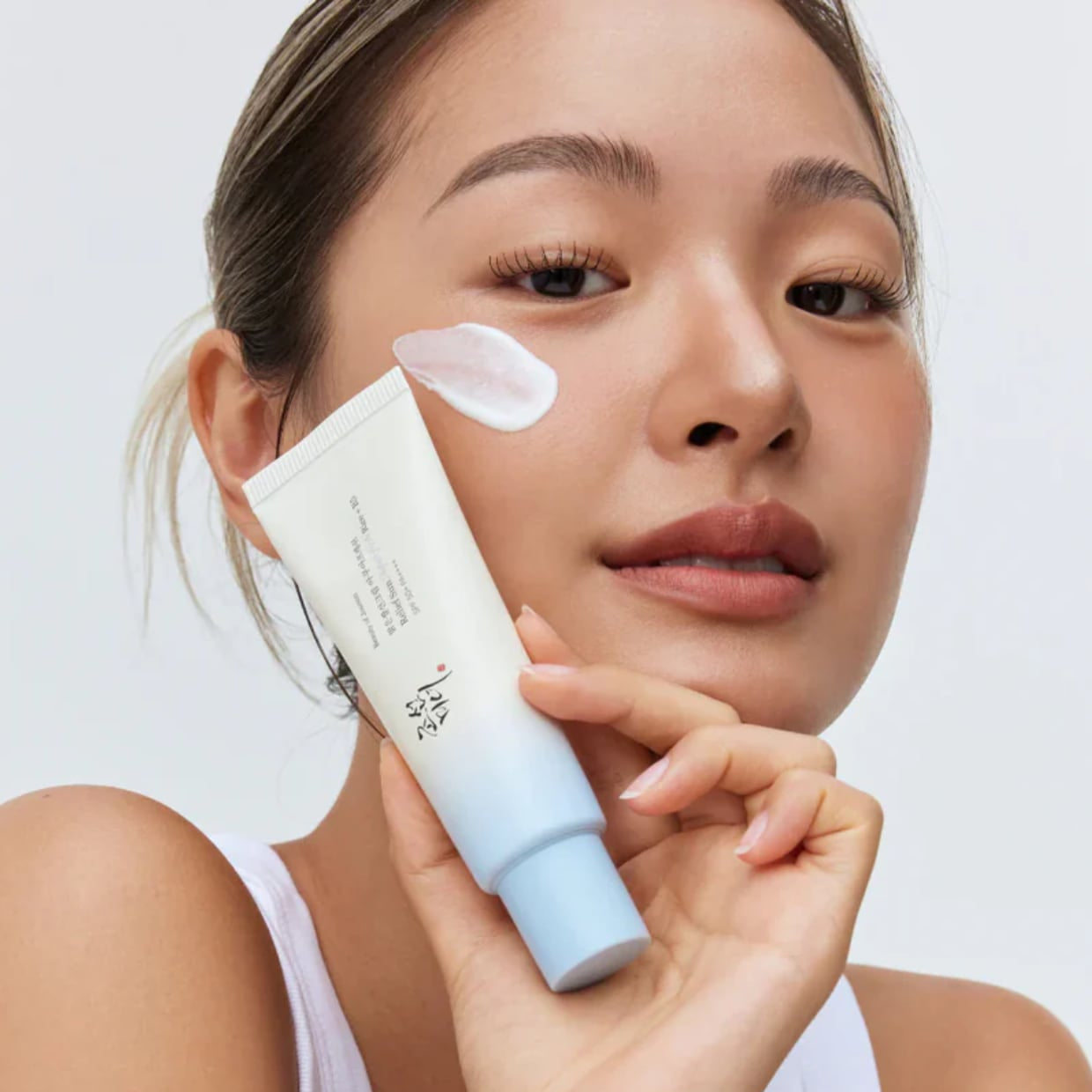 BEAUTY OF JOSEON Relief Sun Aqua Fresh SPF50+ PA++++ 50ml, tube sur visage avec application, femme en studio fond clair.