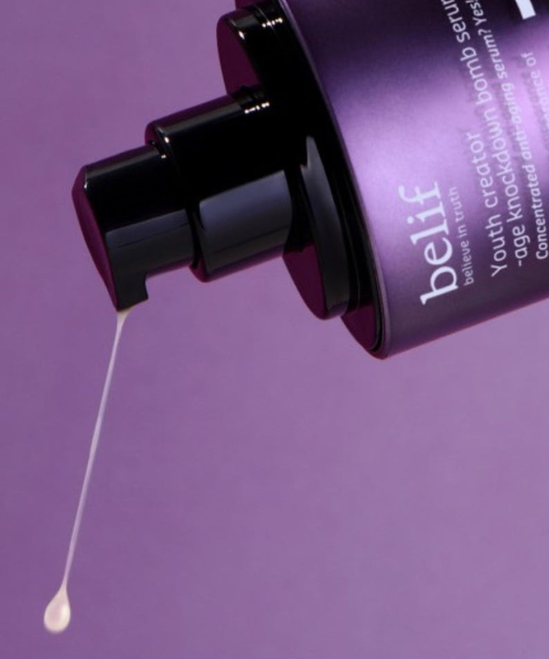 Flacon du sérum BELIF Age Knockdown Bomb Serum 50ml avec pompe en action, fond violet.