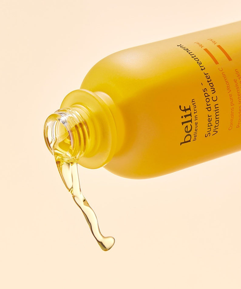 Image du BELIF Super Drops-Vitamin C Water Treatment 150ml, liquide doré coulant d'une bouteille orange, soin visage illuminateur.