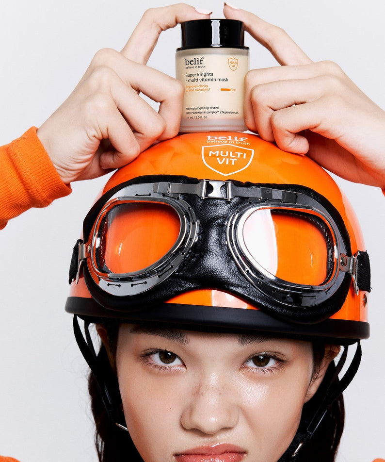 Femme tenant BELIF Super Knights Multi Vitamin Mask 75ml sur un casque orange avec lunettes, soin visage vitaminé.