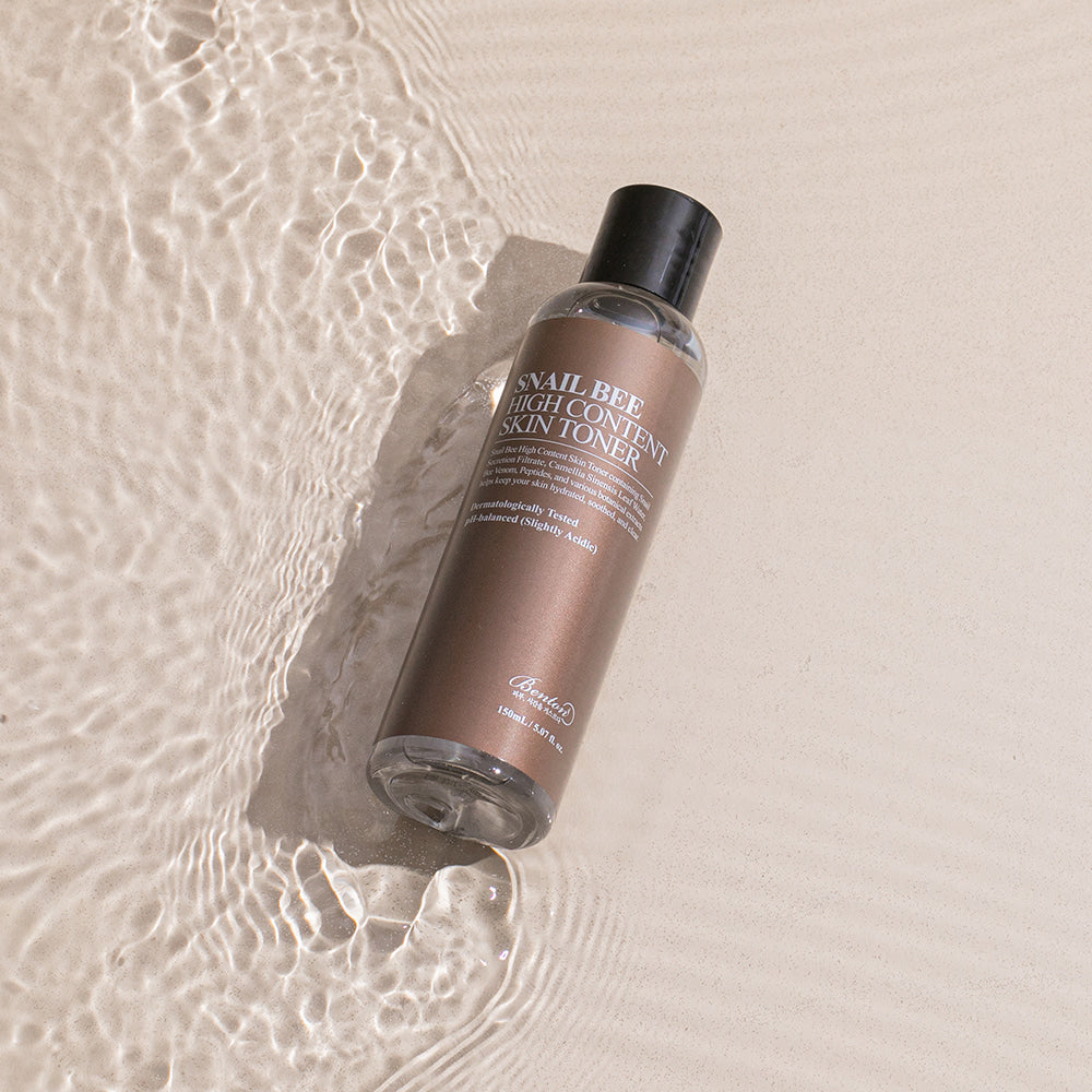BENTON Snail Bee High Content Skin Toner 150ml, flacon sur fond beige avec texture eau et bulles, ambiance skincare.