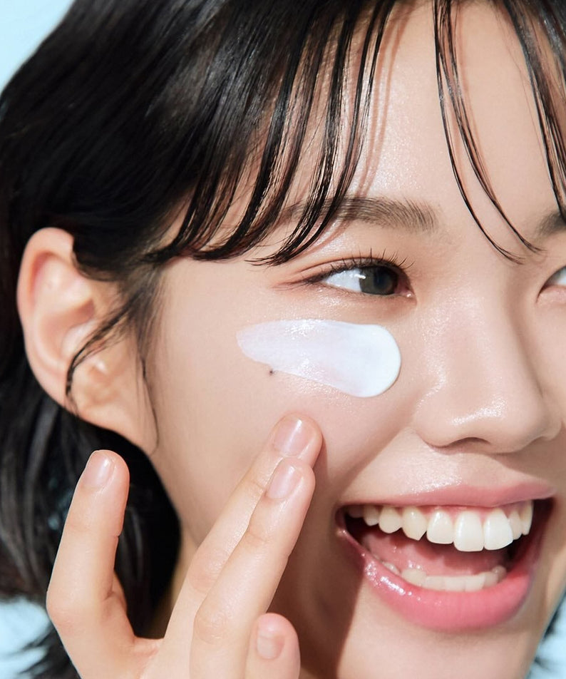 Femme appliquant BEPLAIN Lemon Seed Glutathione Tone-up Sun Cream 50ml sur le visage, protection solaire et éclat radieux.