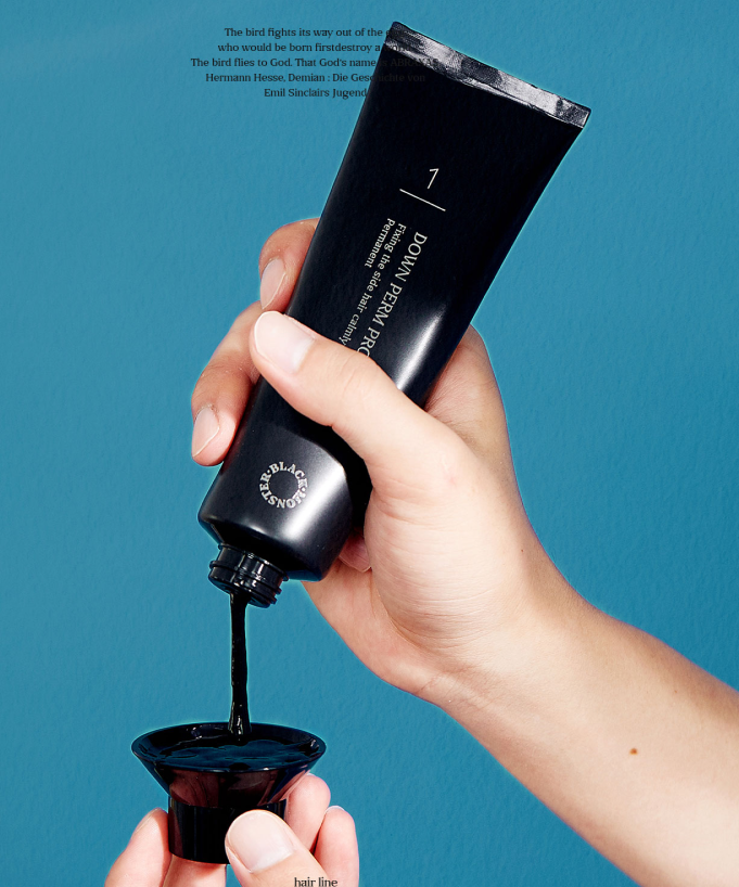 Main tenant BLACK MONSTER  Downperm Pro Kit 120ml, tube noir sur fond bleu, produit coiffure de la marque BLACK MONSTER