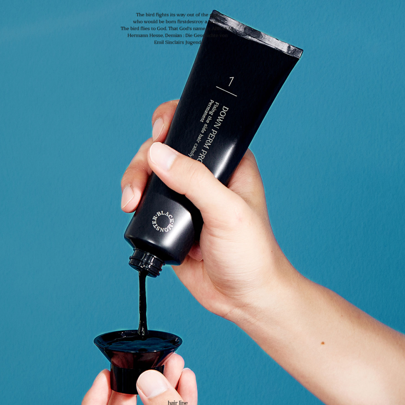 Main tenant BLACK MONSTER  Downperm Pro Kit 120ml, tube noir sur fond bleu, produit coiffure de la marque BLACK MONSTER