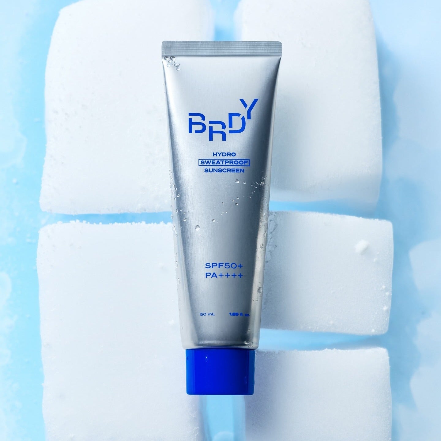B.READY Hydro Sweatproof Sunscreen 50ml de la marque B.READY, tube bleu sur glaçons, soleil et eau, ambiance fraîche
