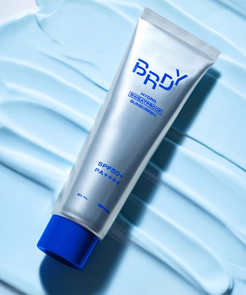 B.READY NEW Hydro Sweatproof Sunscreen 50ml, tube sur tissu bleu texturé, contexte sportif anti-transpiration.