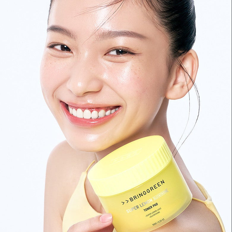 Décris l'image en français : BRINGGREEN Super Lemon Glutathione Toner Pads 90 Pads + 90 Pad Refill Set, femme avec pad jaune