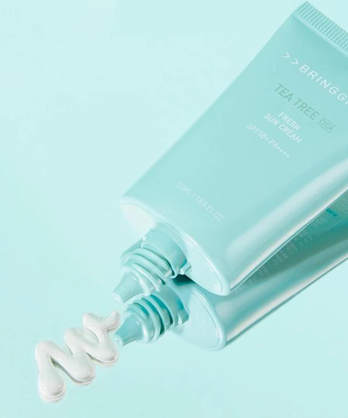 BRINGGREEN Teatree Cica Fresh Sun Cream 50ml de la marque sur fond bleu pastel, tube et gouttes crème visibles.