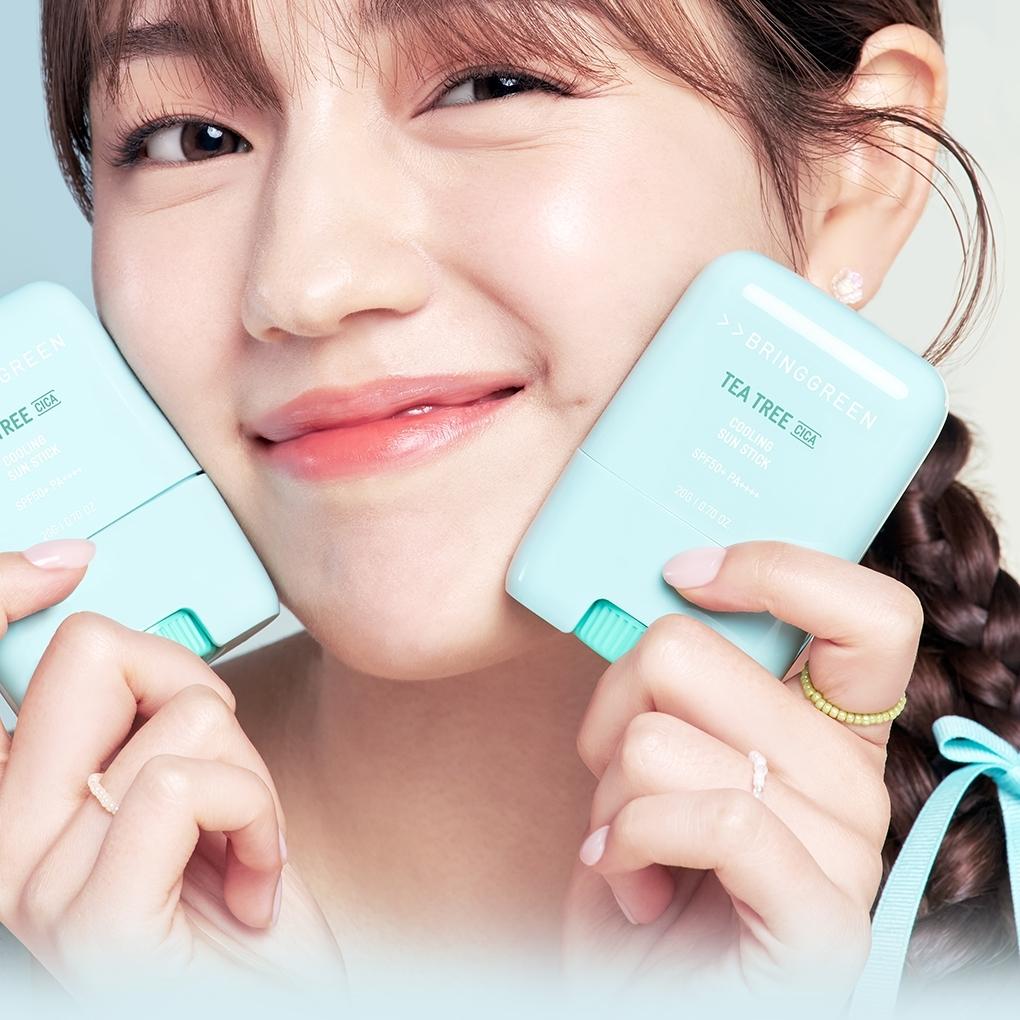 BRINGGREEN Teatree Cica Cooling Sun Stick 20g : jeune fille tenant un stick bleu ciel à la plage, marque en vue.