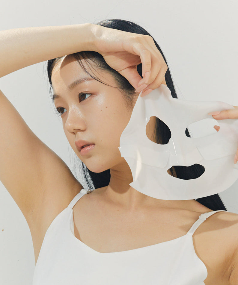 Femme appliquant un BRISKIN Selaginella Exopeptide Collagen Mask 5 sheets sur son visage, illustrant l'utilisation du produit