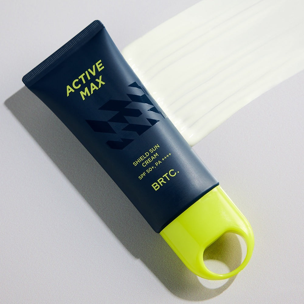 Décris l'image en français : BRTC Homme Active Max Sheild Sunscreen 50ml, tube bleu, contexte soins visage au soleil.