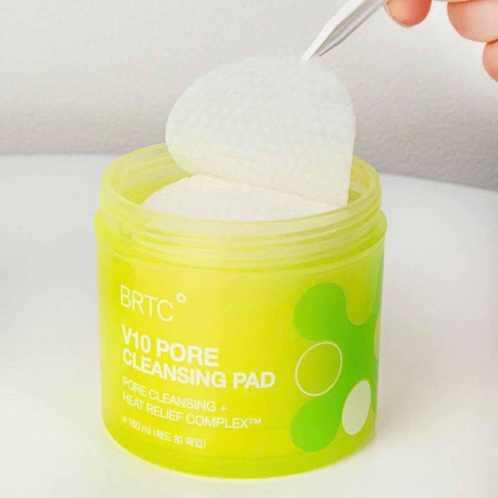 BRTC V10 Pore Cleansing Pad 80p 165ml : boîtier vert avec disque blanc ouvert, main tenant l’accessoire, salle de bain