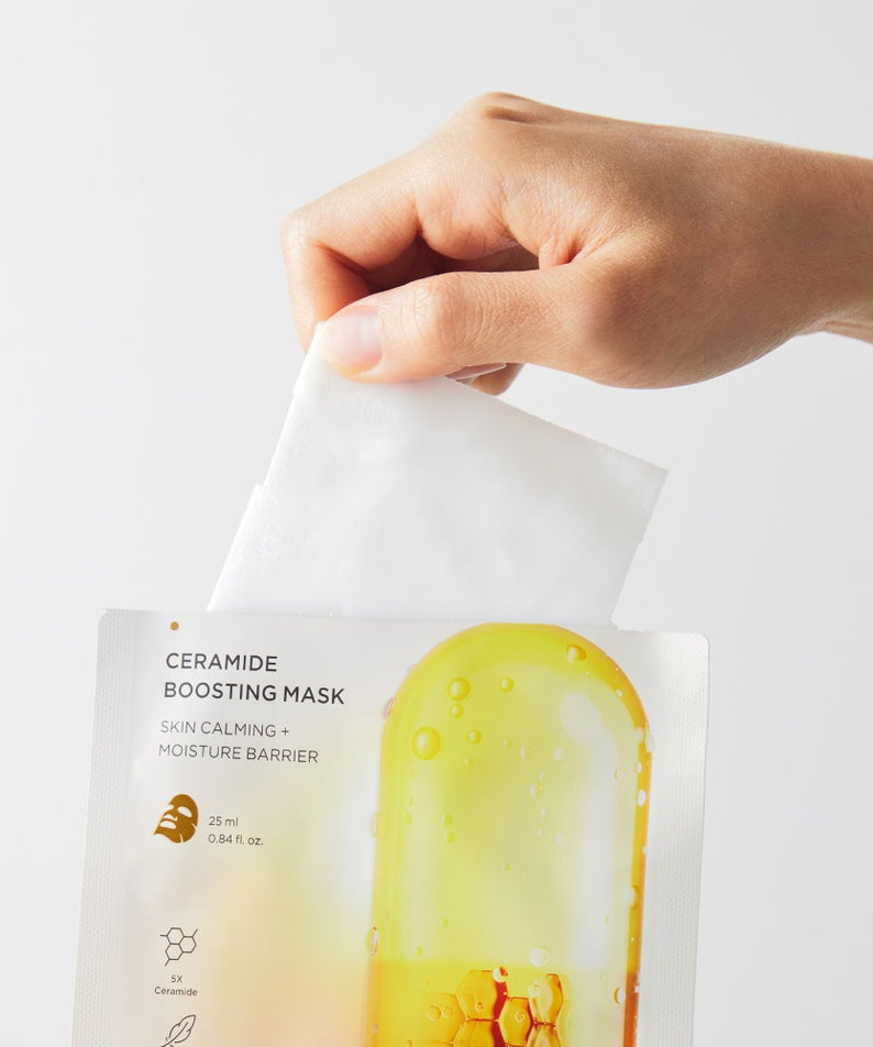 BRTC Ceramide Boosting Mask 10 Sheets avec une main retirant un masque de l'emballage, idéal pour calmer la peau et renforcer l'hydratation.