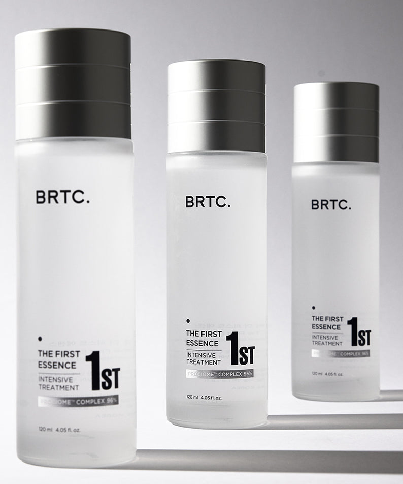 Trois bouteilles de soins BRTC The First Essence 120ml sur fond blanc, produit de beauté pour une peau éclatante et hydratée.