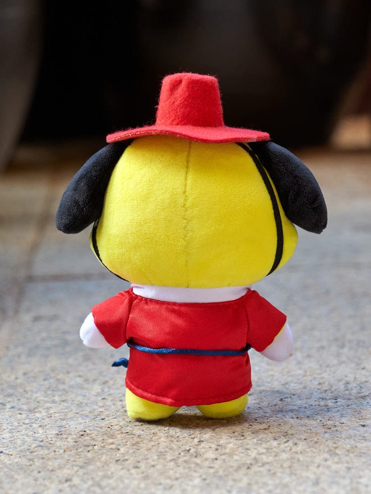 BT21 CHIMMY BABY PLUSH DOLL K-EDITION 2 : peluche officielle CHIMMY, chiot jaune au chapeau rouge, décor sur sol, studio.