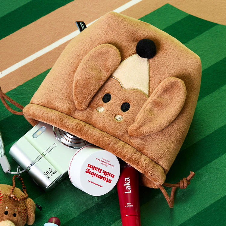 BT21  Joguman Woody Baseball String Pouch de la marque BT21, pochette peluche sur terrain vert, près d’accessoires.