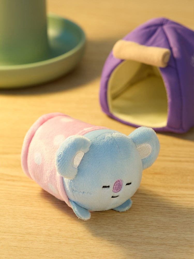 BT21 KOYA DOLL CAMPFIRE peluche koala KOYA de LINE FRIENDS, en scène sur table avec mini tente pour ambiance camping.