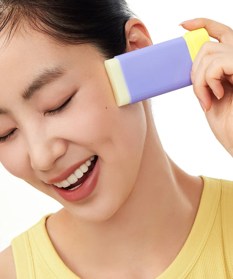 Femme utilisant le BY WISHTREND Pore Smoothing Bakuchoil Sun Stick 18g sur le visage, produit de soin solaire lissant.