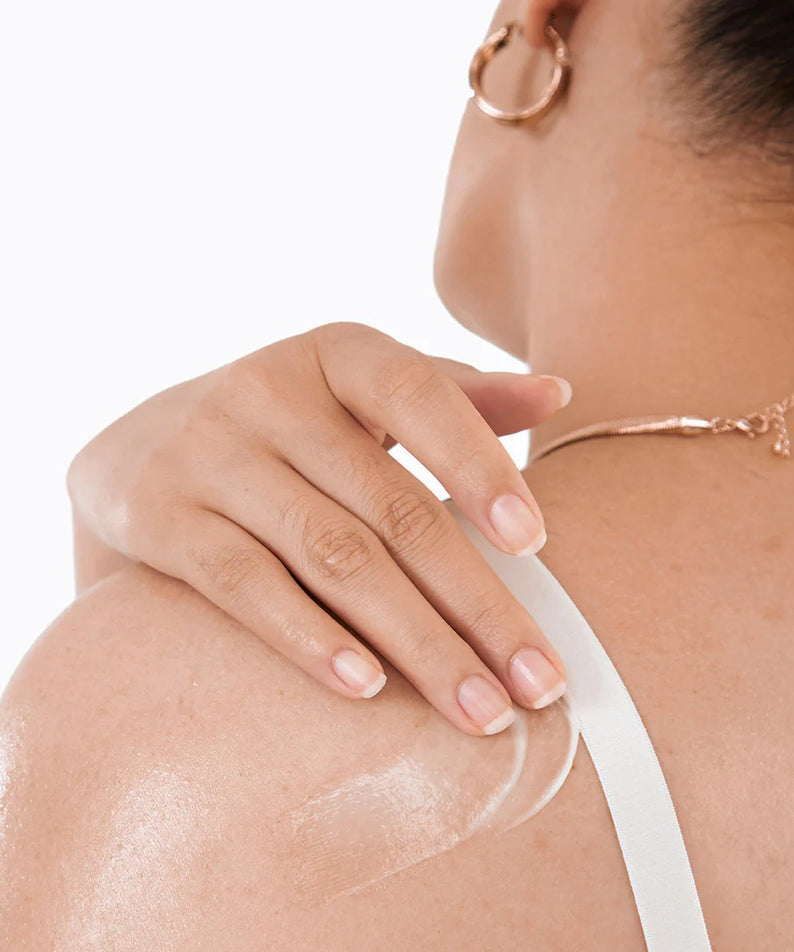 Femme appliquant BY WISHTREND Vitamin A-mazing Bakuchiol Body Lotion 150g sur l'épaule pour une peau nourrie et éclatante.