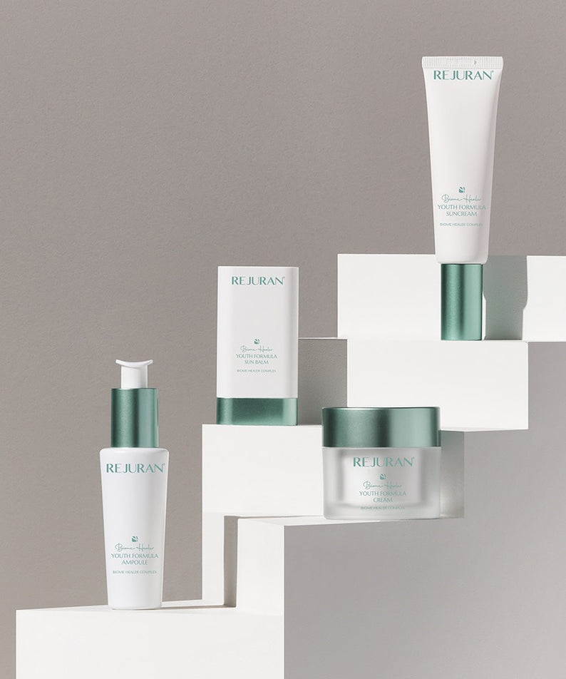 REJURAN Biome Healer Touth Formula Sunscreen 50ml exposé avec autres produits de soins, fond blanc élégant, 140 caractères ou moins.
