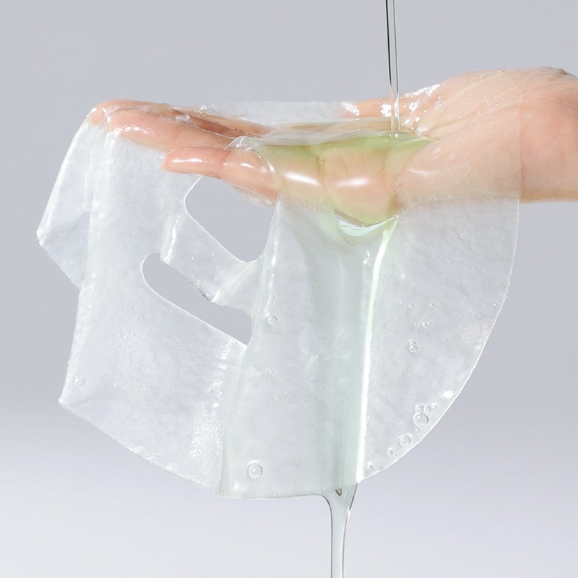 CELIMAX Cica Serum Mask 10 Sheets, main applique un masque en tissu imbibé de sérum cica, vue produit sur fond clair.