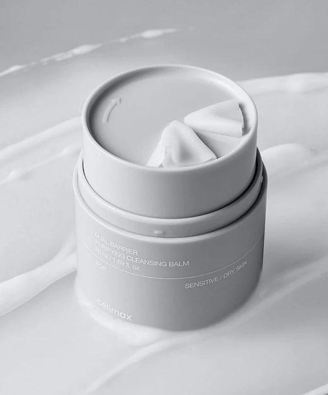 Décris l'image en français : CELIMAX Dual Barrier Purifying Cleansing Balm 50ml de la marque, sur tissu blanc en studio.